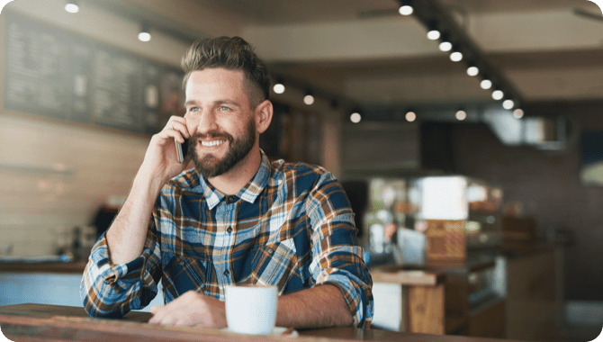 A smiling man on a phone call in a cafeteria
