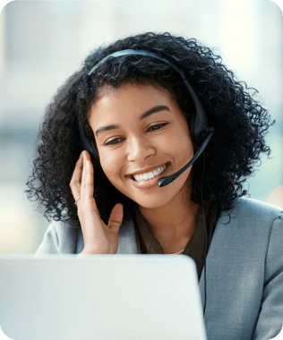 A smiling woman looking at her laptop wearing headphones