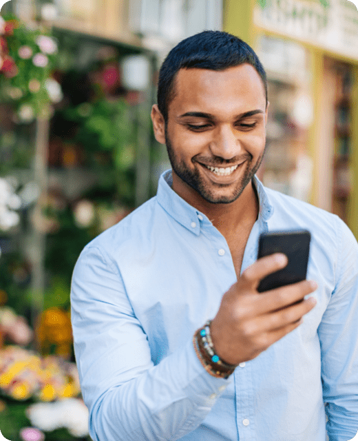 A smiling man in blue shirt looking at his phone