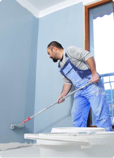 a man running a paint roller on the wall